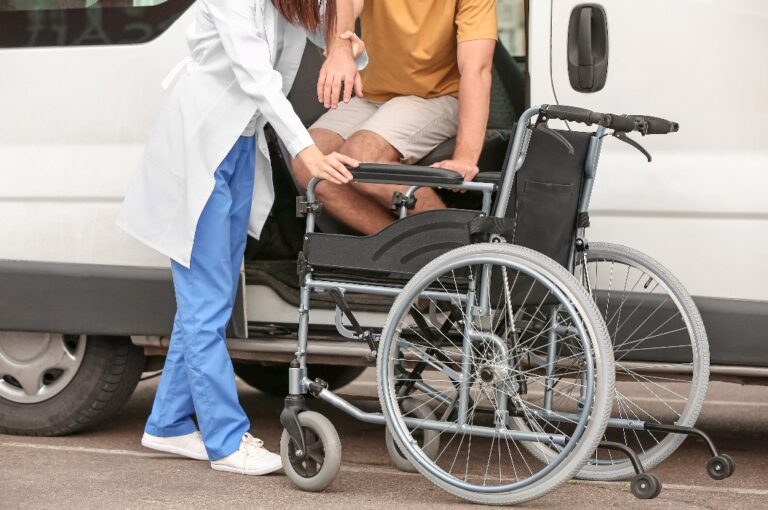 Ein Arzt hilft einem behinderten Mann, sich ins Auto zu setzen