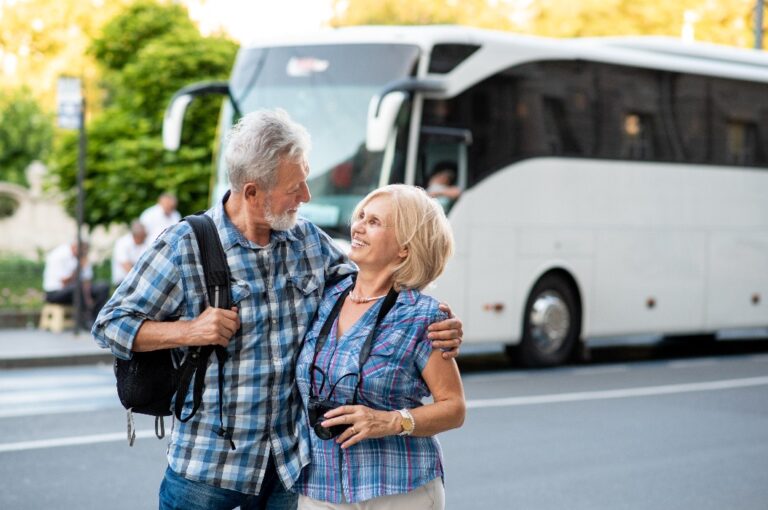 Ein glückliches älteres Touristenpaar, das sich vor einem Reisebus umarmt